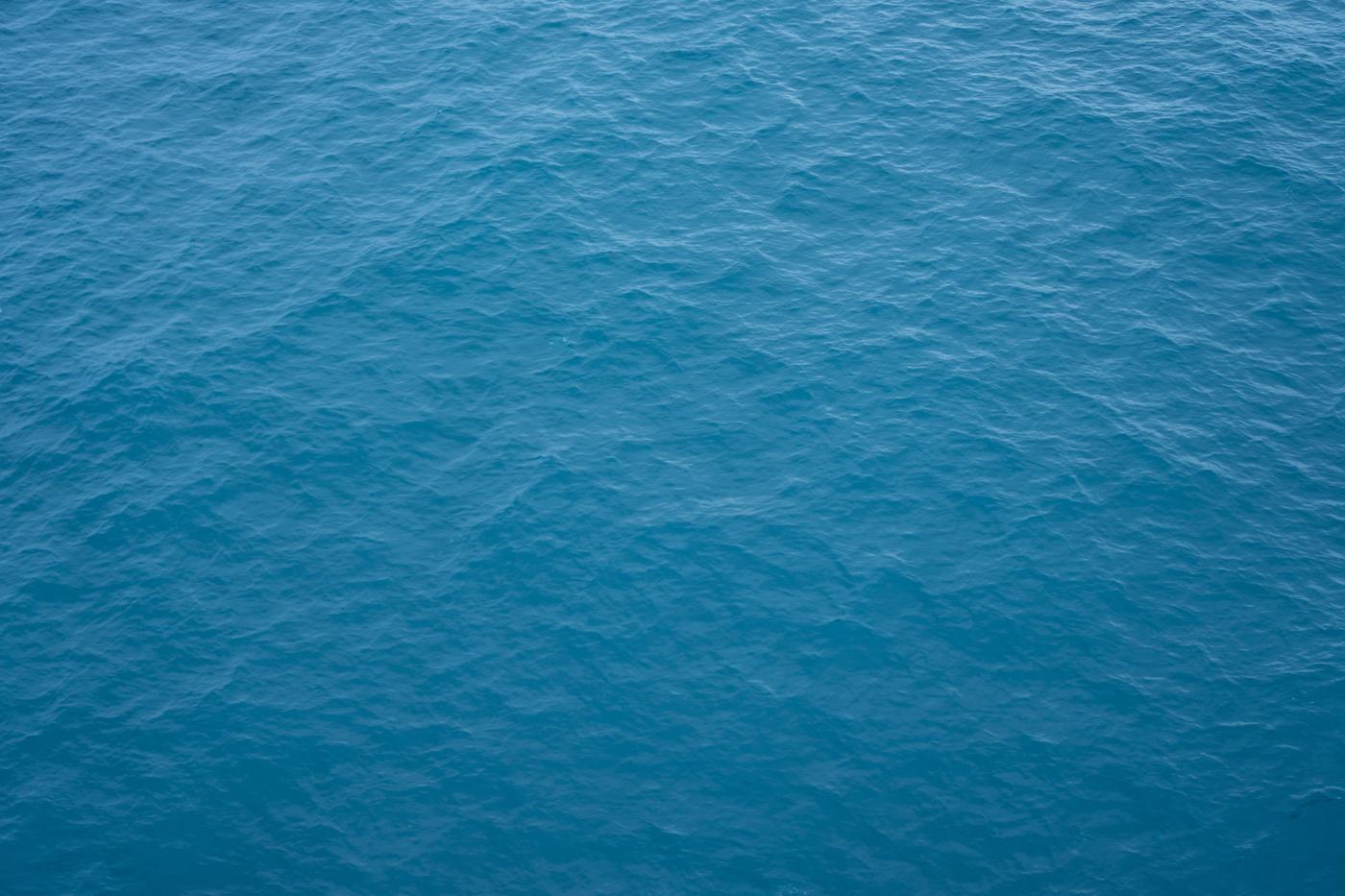 Open ocean surface in soft blue light, with no horizon and no land in the frame